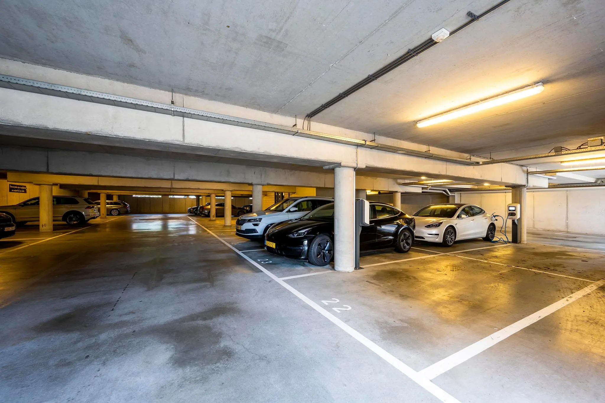 Ondergrondse parkeergarage aan de K.P. van der Mandelelaan met geparkeerde elektrische auto's bij laadpalen.